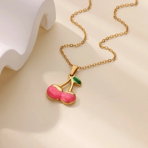 Detailed macro view of a pink enamel cherry pendant on a thin gold chain necklace