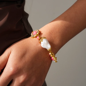 Close-up of vintage gold bracelet with pink gemstone and baroque pearl on wrist