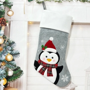 Detail of hanging grey Christmas stocking featuring a cute 3D penguin and snowflake embroidery