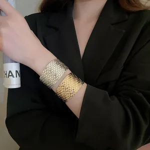 Detail showing two wide woven texture open bangles in gold and silver finish