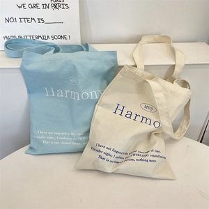 Detail of light blue and beige canvas tote bags featuring poetic typography and MFS lettering