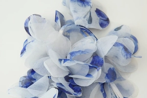 Détail d'une fleur en tissu organza dégradé bleu et blanc avec des pétales superposés