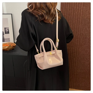 Pale pink patent leather handbag with bow detail shown on a model from the back