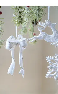 Close-up of white flocked Christmas tree ornaments with silver glitter and red berries