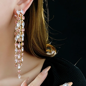 Close-up of pink and white marquise-cut crystal tassel earrings on golden plating