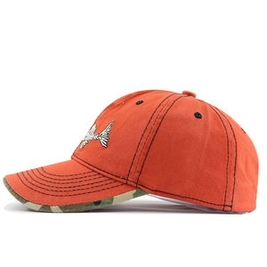 Detail of vibrant orange baseball cap with fishbone embroidery and camo brim bottom