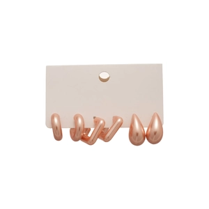 Three pairs of rose gold acrylic earrings set with round and teardrop shapes on a card