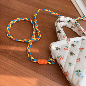 Detail of quilted white cotton bag with bear floral prints and colorful braided rope strap