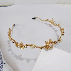 Nahaufnahme des goldenen Blumen-Haarreifens mit Kristallen und eleganten Perlen
