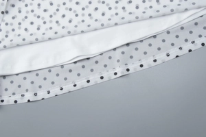 Close-up of black polka dot mesh fabric with white lining and high-quality hem stitching