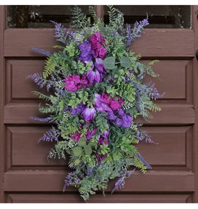 Detailed view of teardrop purple tulip and lilac door wreath on dark wooden background