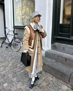 Détail d'un gilet en peau lainée vintage marron superposé à une robe fleurie et un sac chic