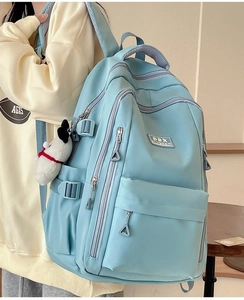 Detail view of light blue ergonomic backpack with side buckle and plush puppy charm