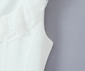 Detailed close-up of white floral lace neckline and stitching on a mini dress