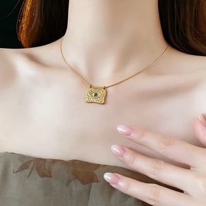 Dettaglio di una collana a catena serpente dorata con pendente vintage a forma di occhio