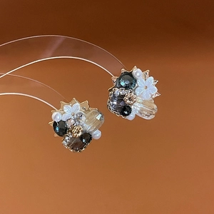 Detail of floral earrings with mother of pearl, crystals and pearls on gold base