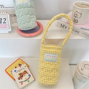 Close-up of quilted heart pattern and embroidered label on yellow checkered cup carrier bag