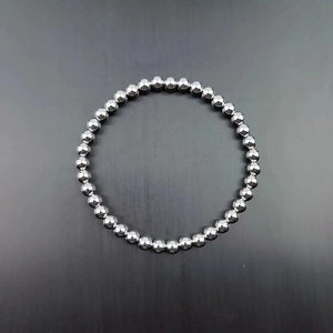 Polished silver stainless steel beaded stretch bracelet for women on a dark grey background