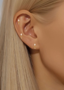 Macro view of gold flower cartilage piercing earrings with clear crystals on ear