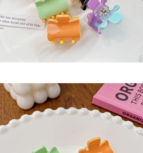 Close-up of colorful candy-colored mini hair claws in a decorative white ceramic bowl
