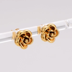 Stereoscopic rose stud earrings in gold finish on a display stand with white background