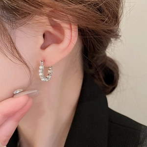 Detailed view of silver hoop earrings with white pearls and sparkling rhinestones on a model