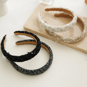 Detailed view of four tweed headbands in black and beige displayed on a stone slab