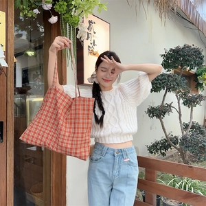 Detail of red gingham cotton tote bag carried by a model in casual summer outfit
