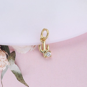 Detailed view of a gold cactus pendant featuring a round clear gemstone on a floral background