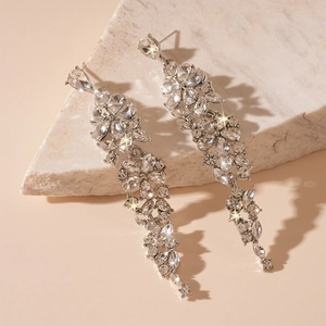 Detail of elegant silver tassel earrings with flower crystal clusters on marble surface