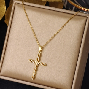 Golden cross necklace with inlaid zircon on stainless steel chain over a jewelry box