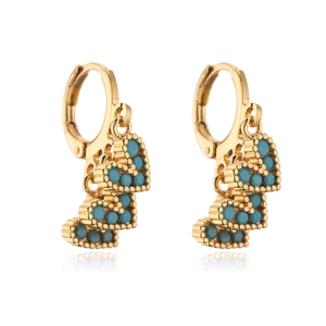 Detail view of gold heart drop earrings with turquoise beads and hoop closure