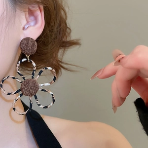 Détail de grandes boucles d'oreilles fleur en tissu avec imprimé léopard et centre brun