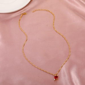 Close-up of golden necklace with a red heart pendant on pink silk background