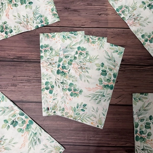 Rectangular floral paper napkins with watercolor eucalyptus and berry prints on wood