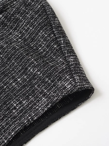 Dettaglio ravvicinato della trama in tweed bianco e nero che mostra il tessuto a maglia