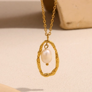 Détail d'un pendentif ovale martelé plaqué or 18K avec une perle sur un collier