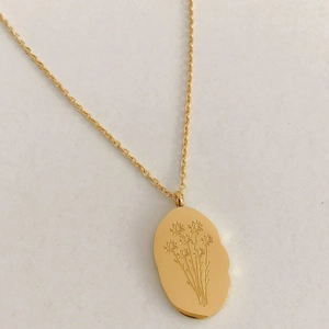 Gros plan détaillé du pendentif ovale irrégulier doré avec motif floral gravé élégant