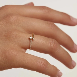 Close-up of a gold cocktail ring with a round clear stone and pave-set diamond accents