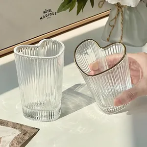 Elegant heart-shaped glass cup with vertical texture and gold rim in natural light