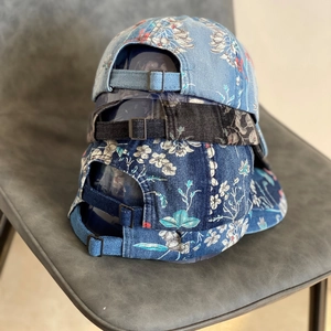 Detail view of denim floral baseball caps with metal adjustment buckles and pattern texture