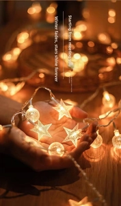Detail of warm white star-shaped LED fairy lights held in hand with soft bokeh background