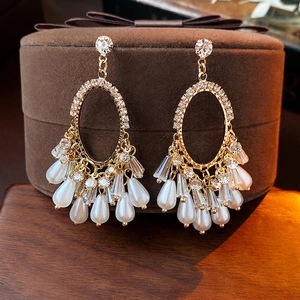 Vintage gold oval earrings with tassels and pearls displayed on a velvet jewelry box