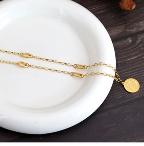 Close-up of golden sunflower smiley face pendant with oval link chain on white plate
