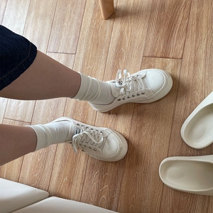 Detailansicht weißer Segeltuchschuhe kombiniert mit schlichten weißen Baumwollsocken