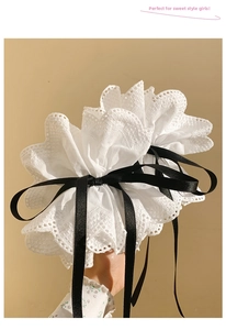 Détail de l'accessoire en dentelle blanche à froufrous avec un nœud en ruban satiné noir