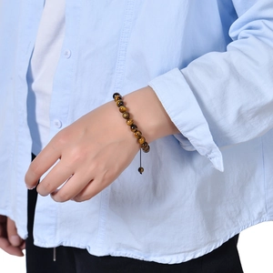 Detailed view of natural tiger eye beaded bracelet on wrist with adjustable black cord