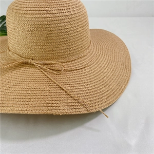 Close-up of tightly woven paper straw sun hat featuring a delicate bow detail and natural texture