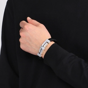 Detailed view of men's black braided leather bracelet with silver metal clasp on wrist