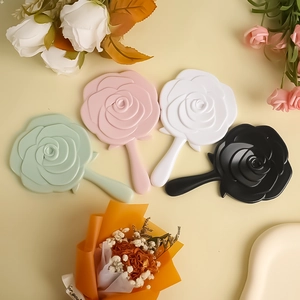 Flat lay of vintage rose shaped handheld mirrors in green, pink, white, and black colors